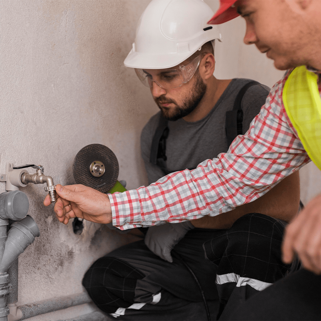 2 plumbers working on an outside faucet