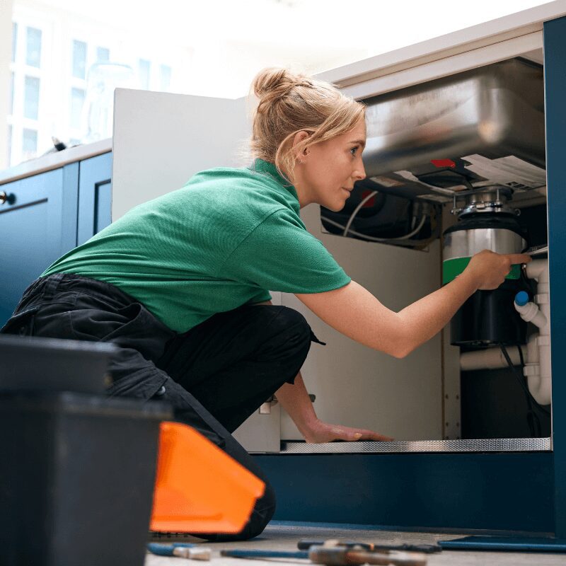 female plumber fixing sink